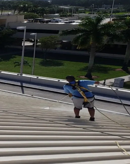Worker in harness on sloped metal roof