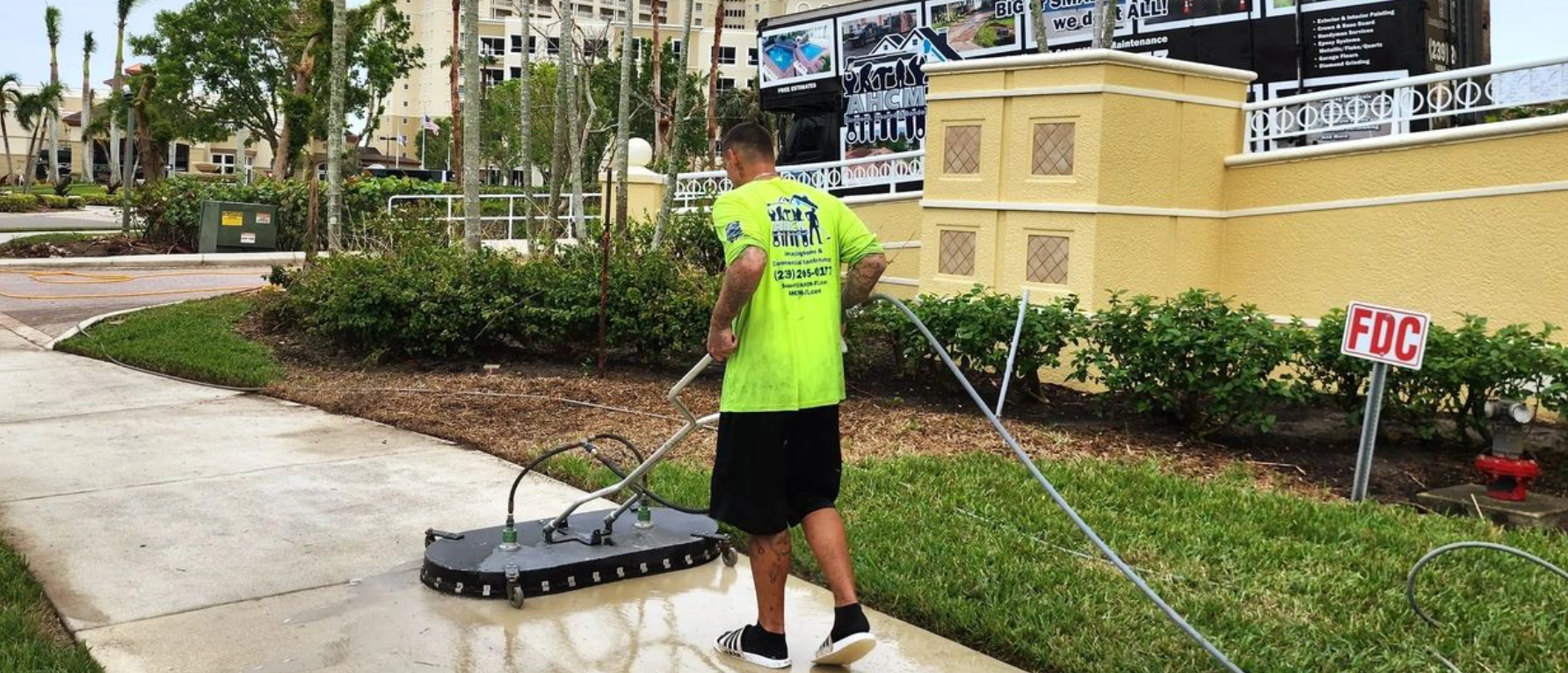 Worker pressure-washing sidewalk with surface cleaner