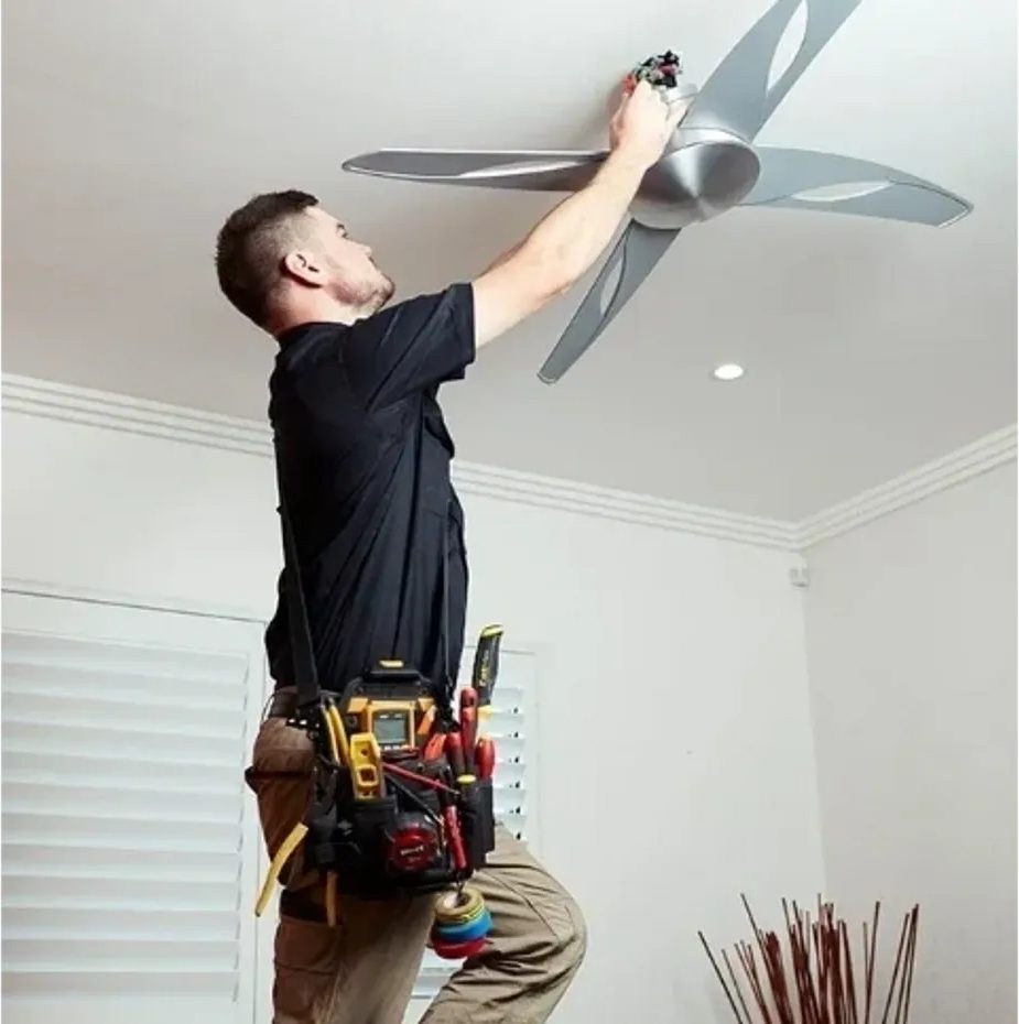 Technician installing silver ceiling fan indoors