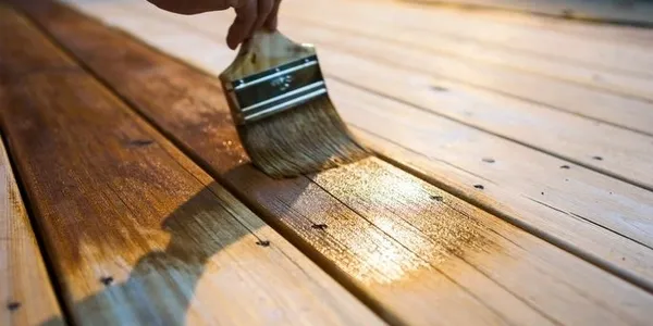 Hand brushing stain onto wooden deck boards