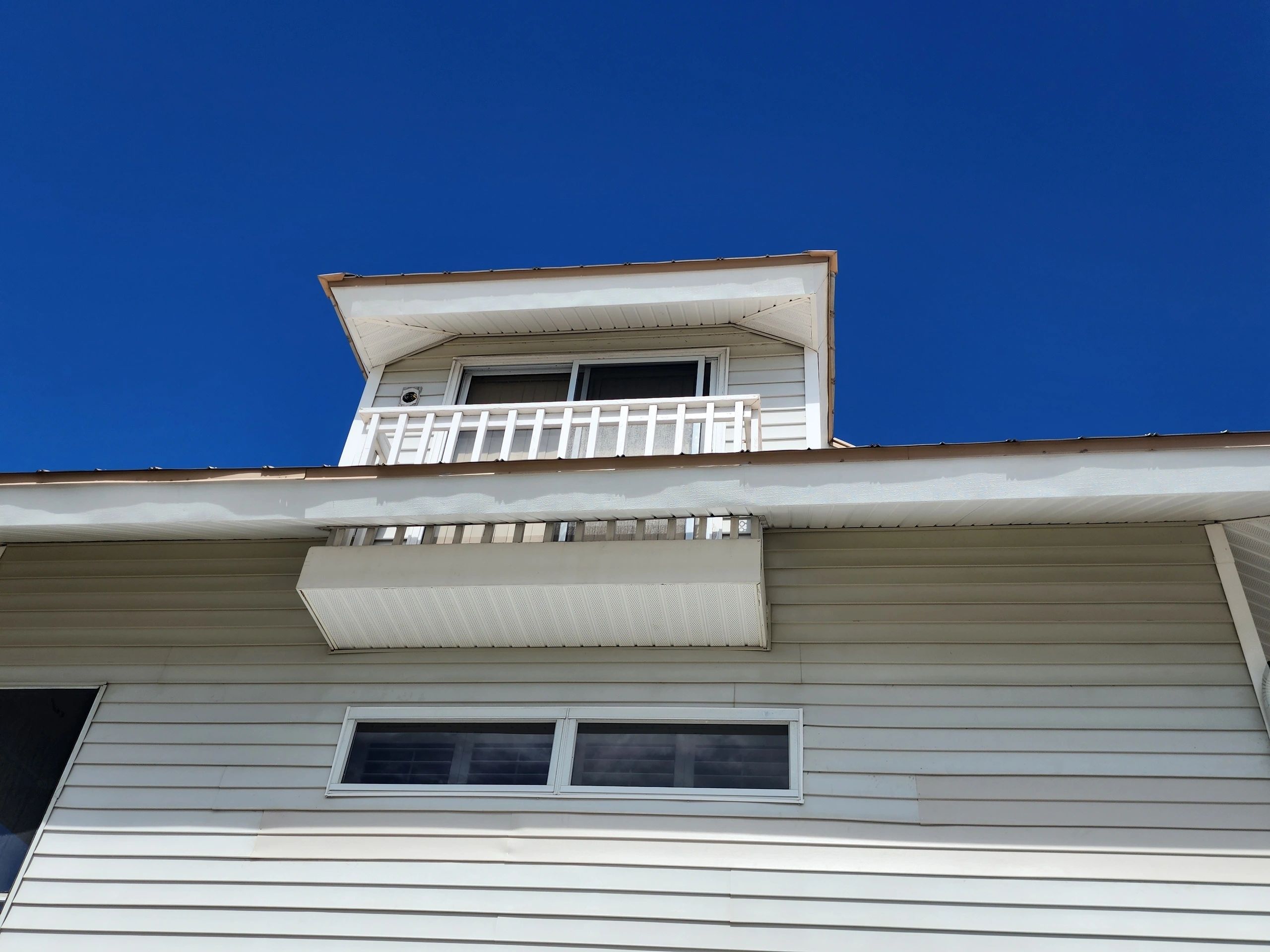 White house dormer and siding under blue sky