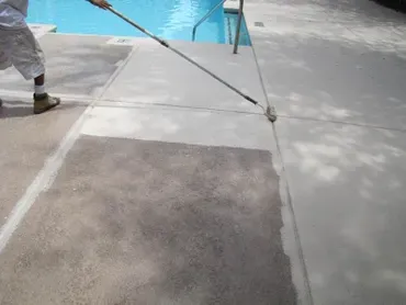 Worker resurfacing pool deck with long roller