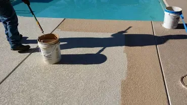 Worker coating pool deck with tan resurfacer