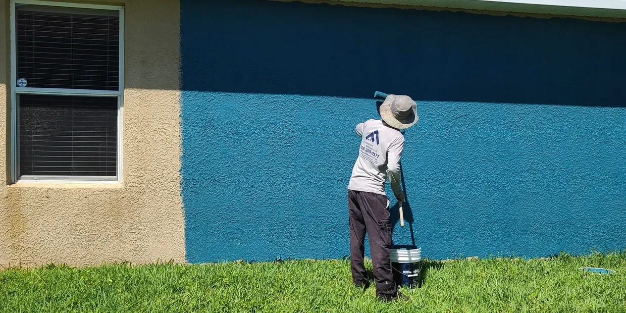 Worker painting house exterior bright blue