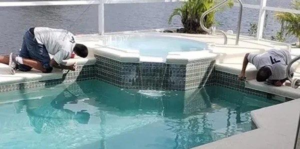 Workers cleaning pool tile and spa area