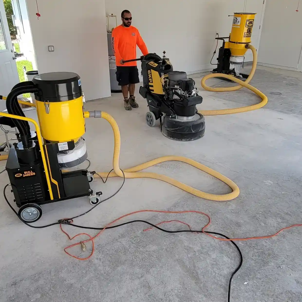Worker using floor grinder with dust collectors