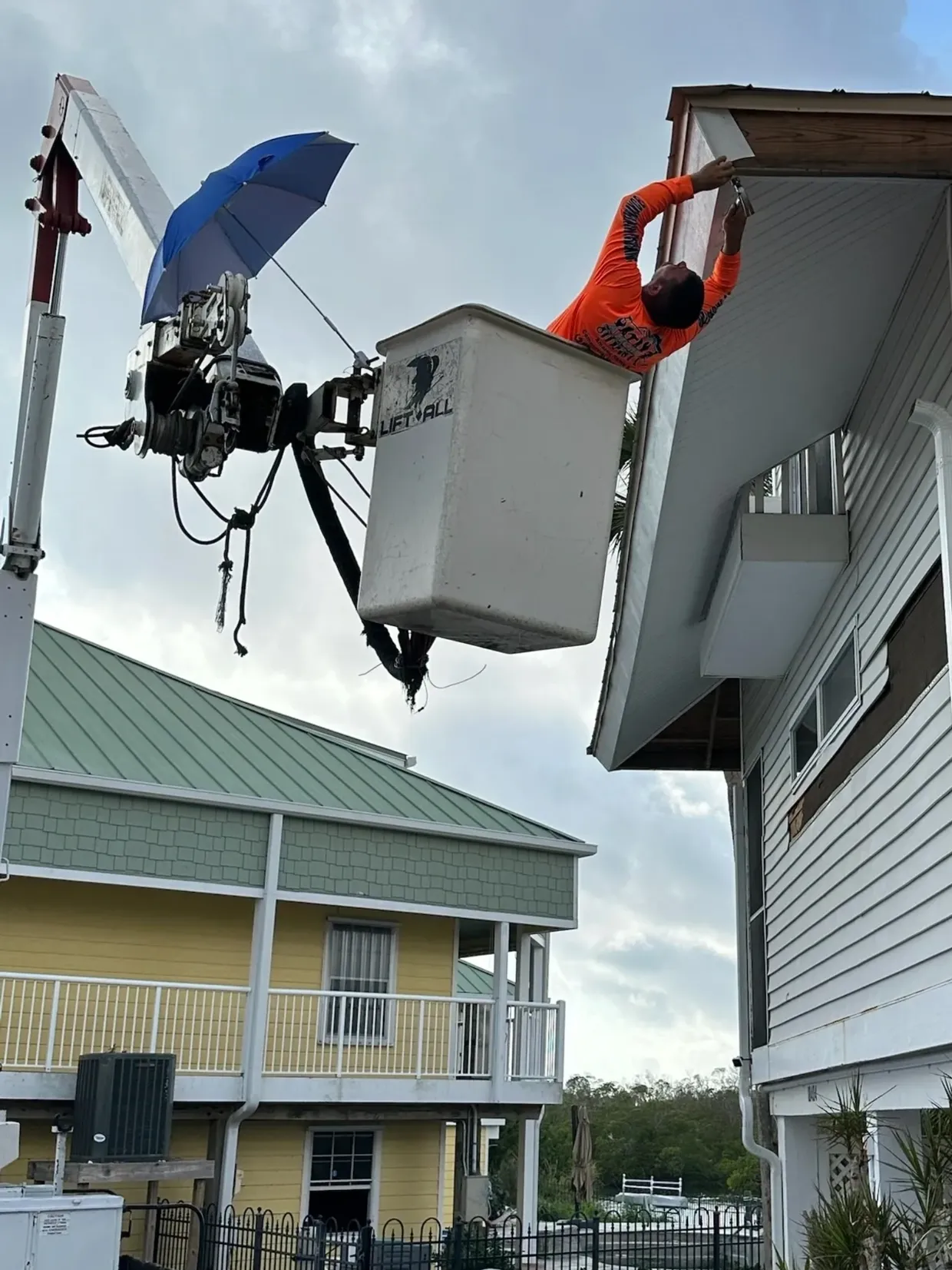 Worker in bucket truck repairing house eaves