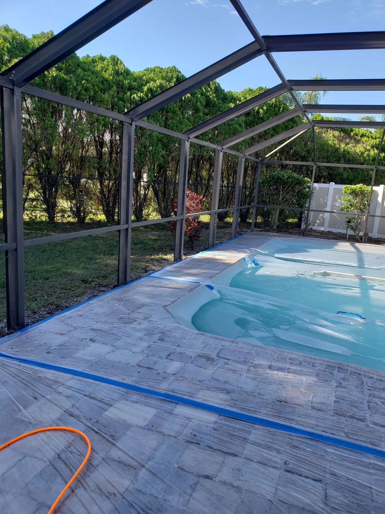 Screened-in backyard swimming pool with tiled deck