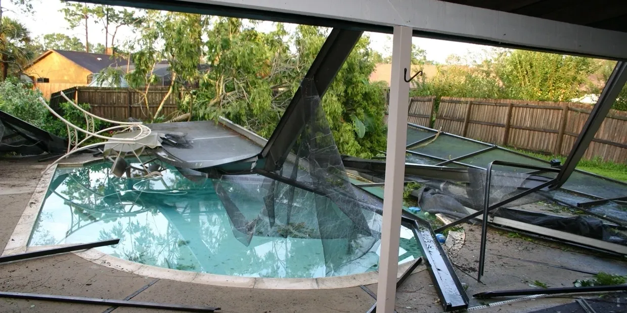 Collapsed pool screen enclosure with broken glass