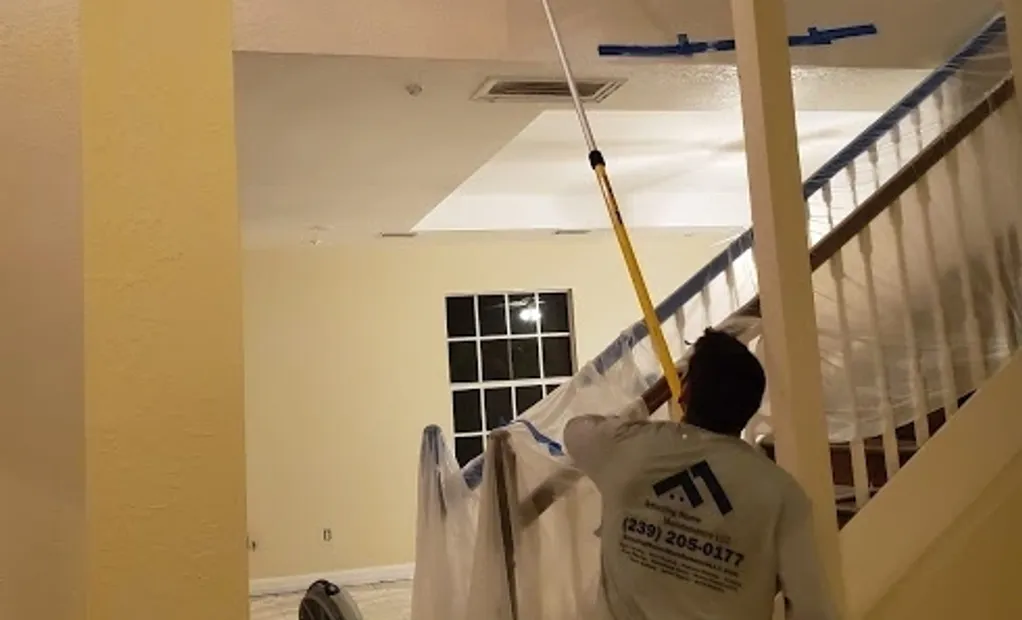 Worker painting interior ceiling with extension pole