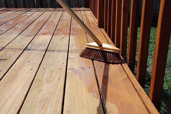 Broom sweeping wet wooden deck boards
