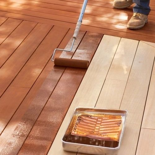 Applying wood stain to deck with roller