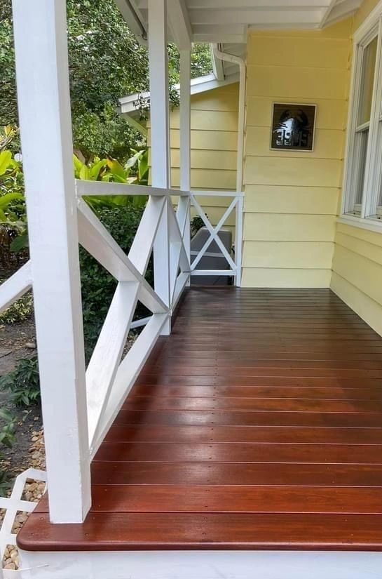 Polished wooden porch, white railing, yellow siding