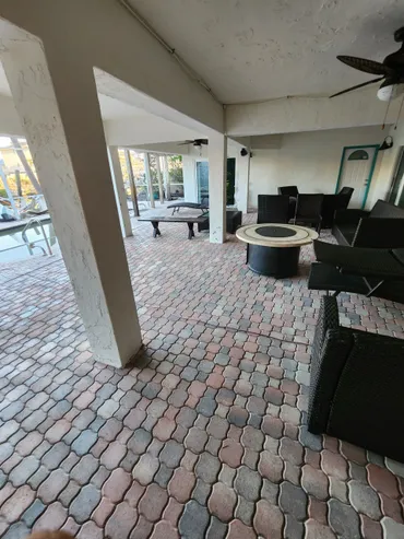 Covered poolside patio with wicker seating and firepit