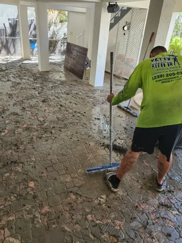 Worker cleaning muddy paver floor under house