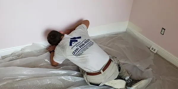 Contractor installing baseboard in pink room