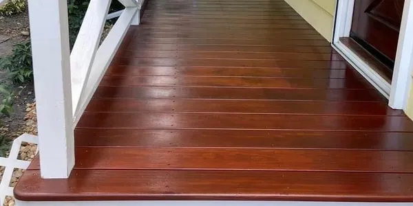 Stained wooden porch floor with white railing