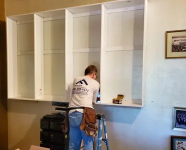 Worker installing white built-in wall cabinets