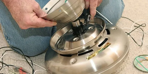 Hands installing ceiling fan motor assembly