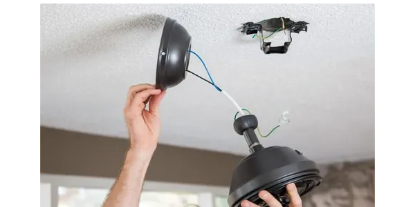 Hands installing black ceiling light fixture
