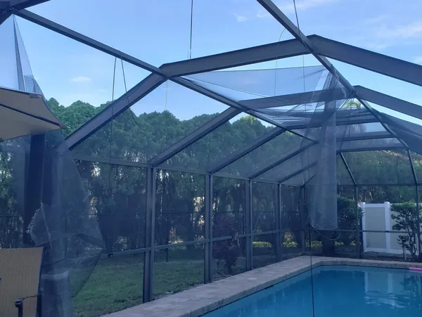 Damaged screened pool enclosure with hanging mesh
