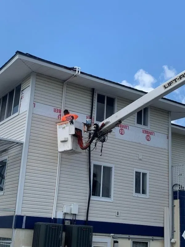 Worker in bucket lift repairing house siding