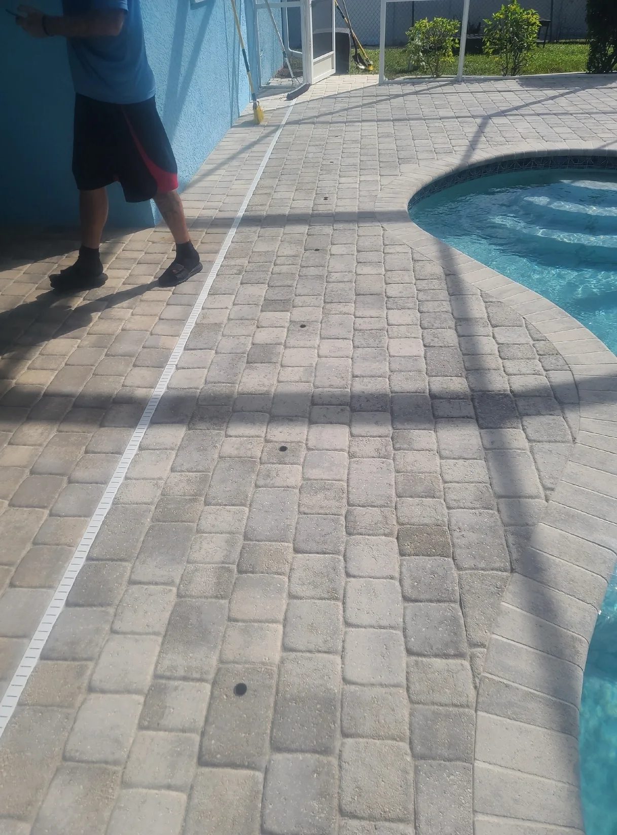 Patio pavers beside curved backyard swimming pool