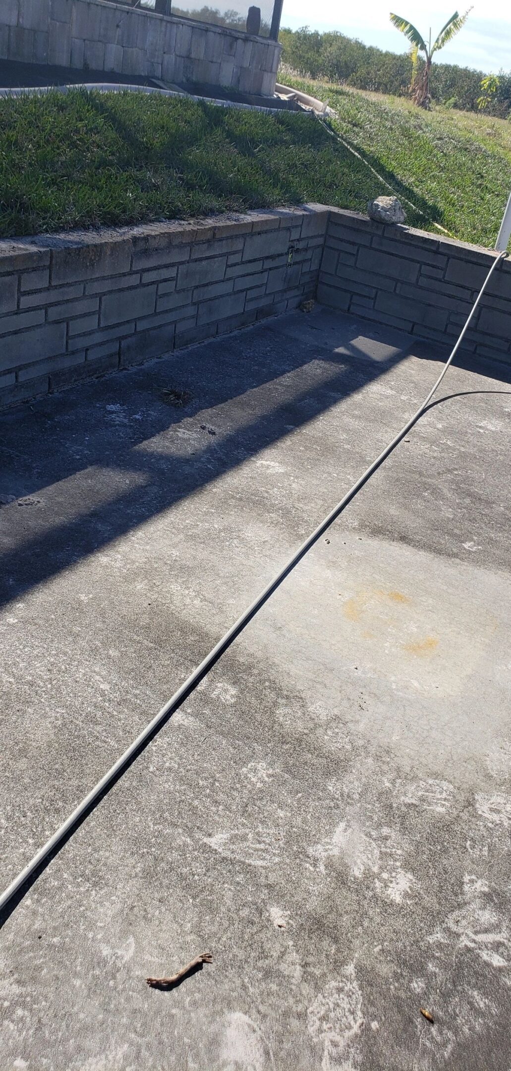 Concrete patio with stone retaining wall and hose