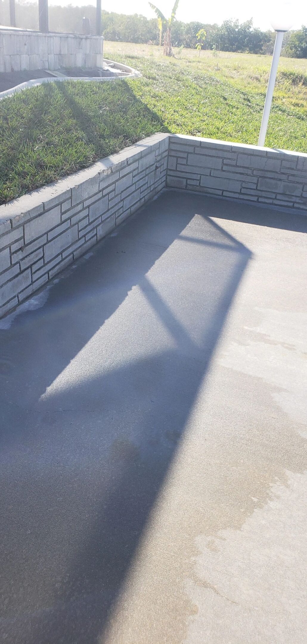 Sunlit concrete patio corner with retaining wall