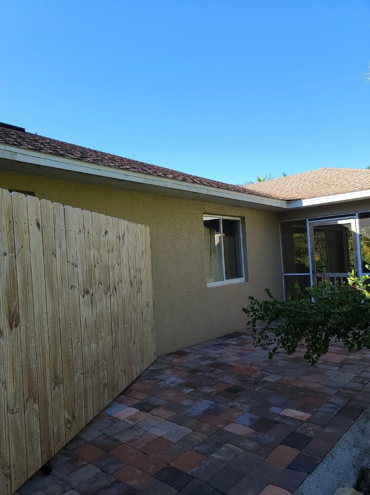 Paver patio beside wooden fence and house