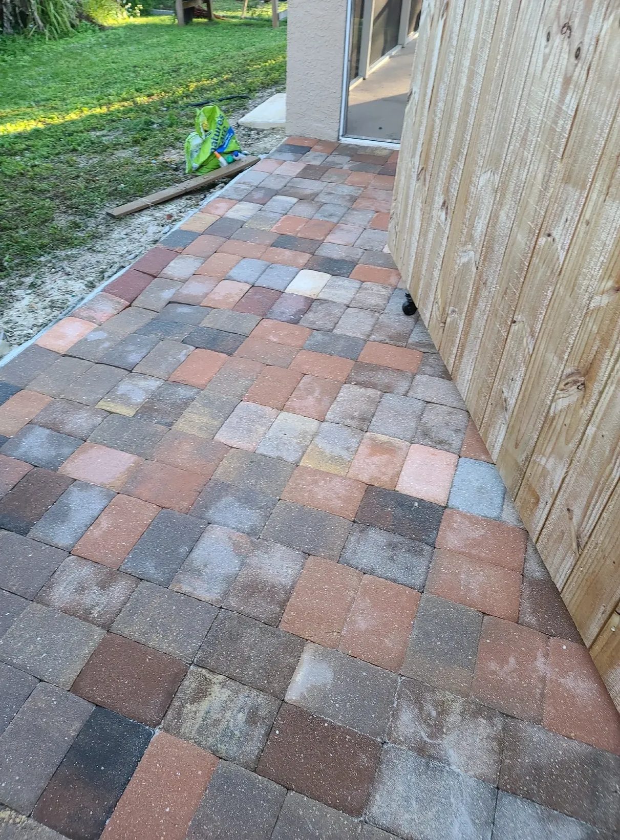 Multicolored square paver walkway beside wooden fence