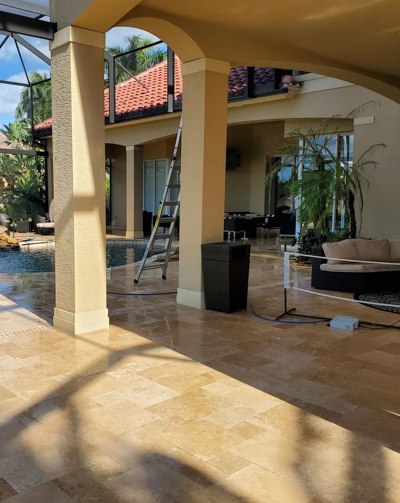 Sunlit poolside patio with columns and ladder