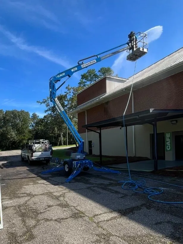 Blue boom lift beside brick building roof