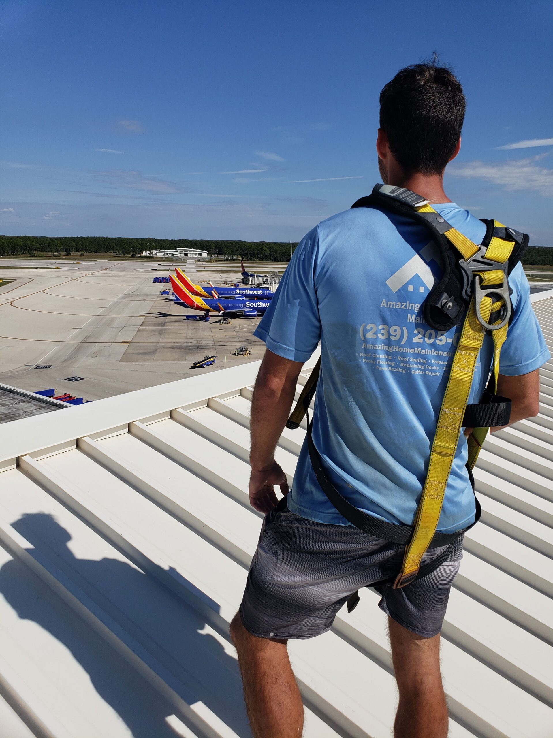 Worker in safety harness overlooking airport runway