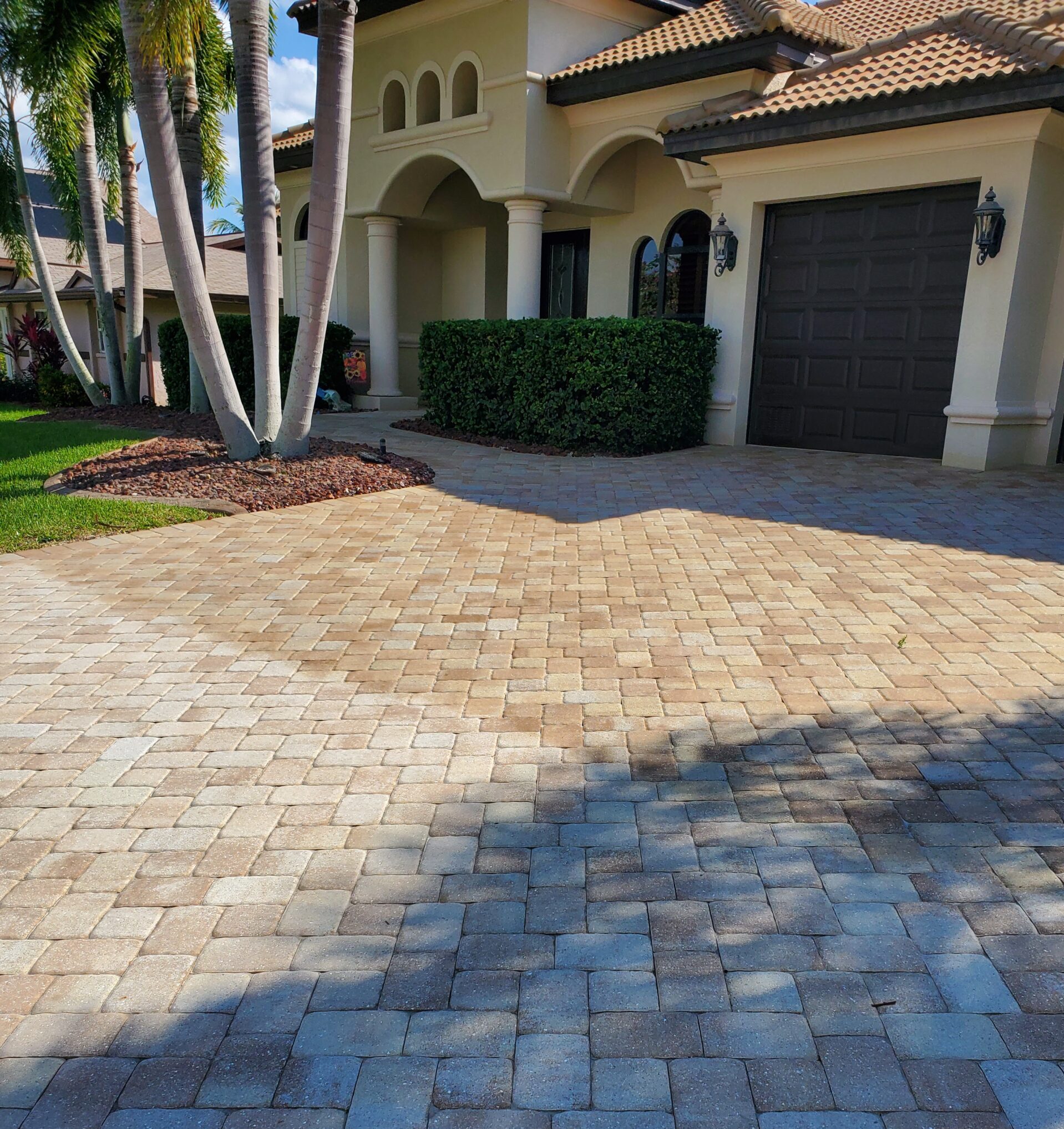 Mediterranean house with paver driveway and palms