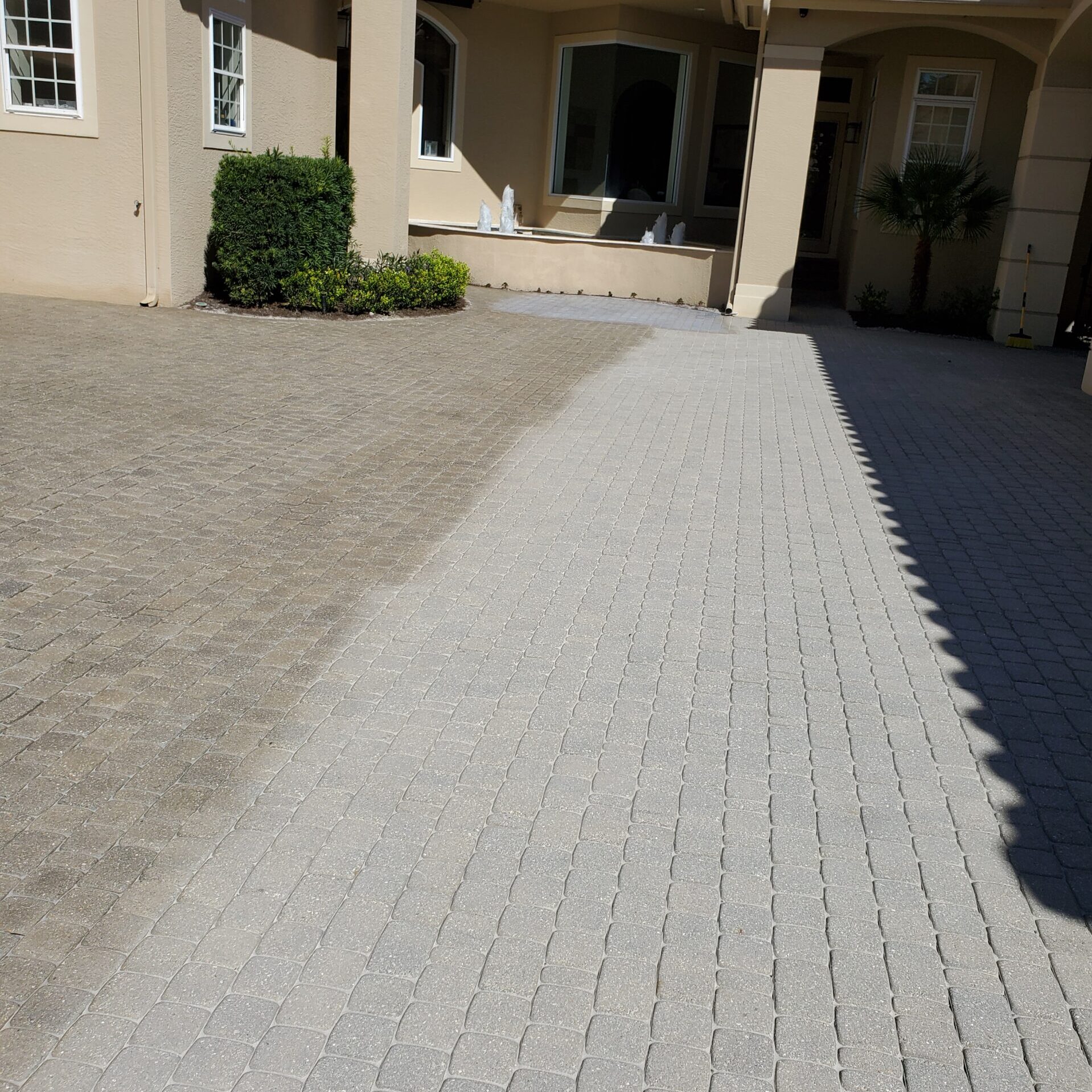 Half-cleaned driveway pavers at house entrance