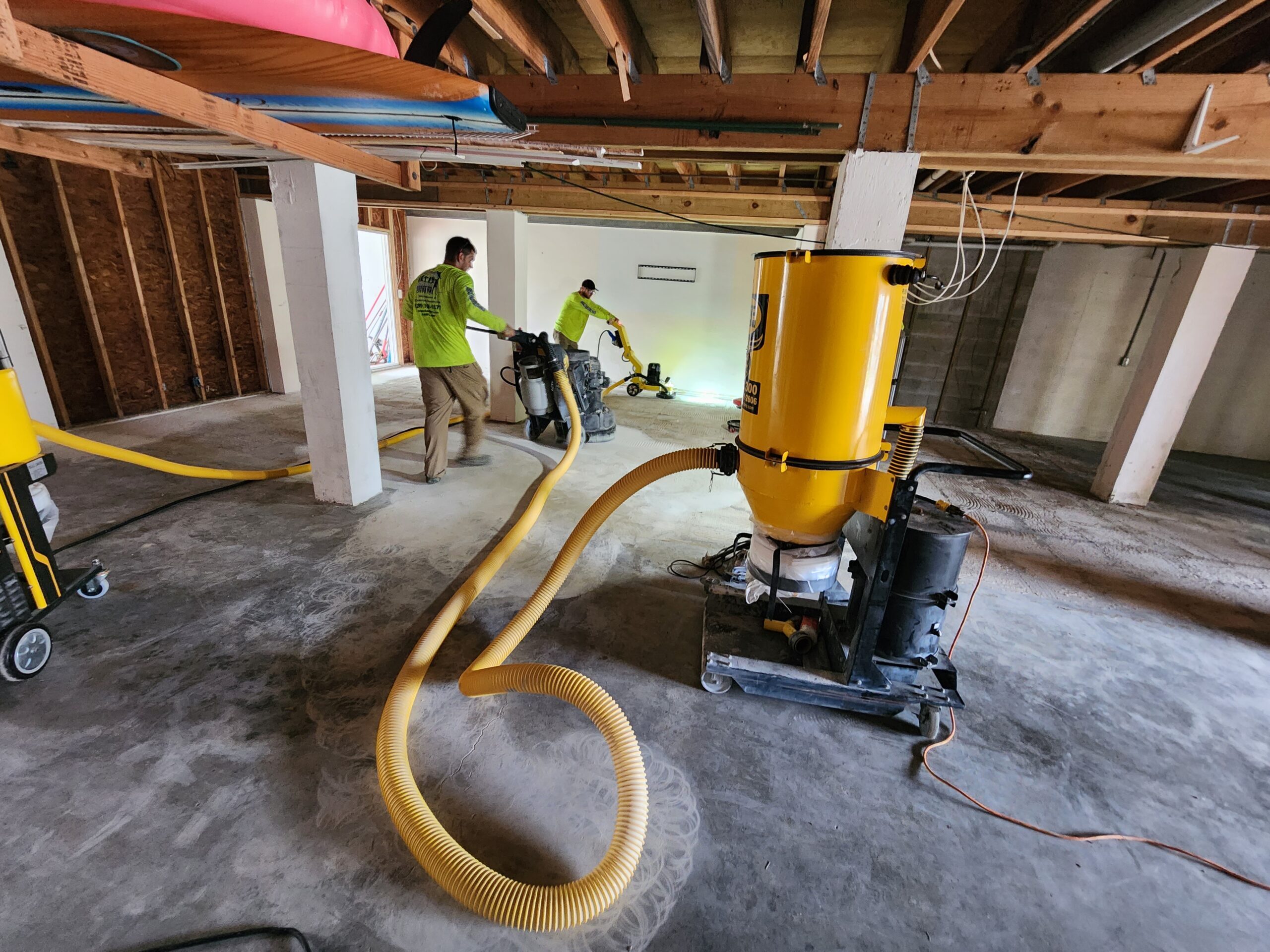 Workers vacuuming concrete basement floor