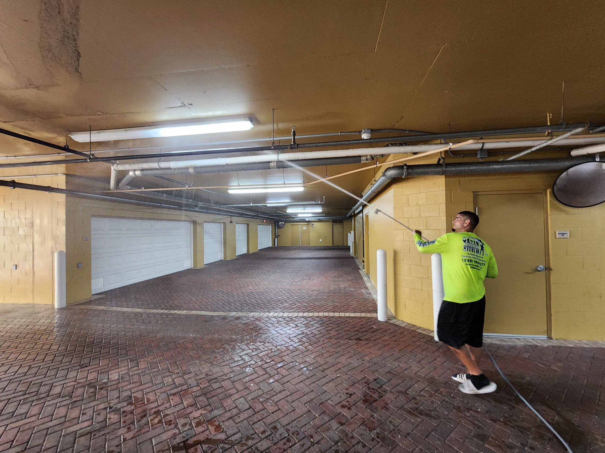 Man cleaning parking garage ceiling with pressure washer