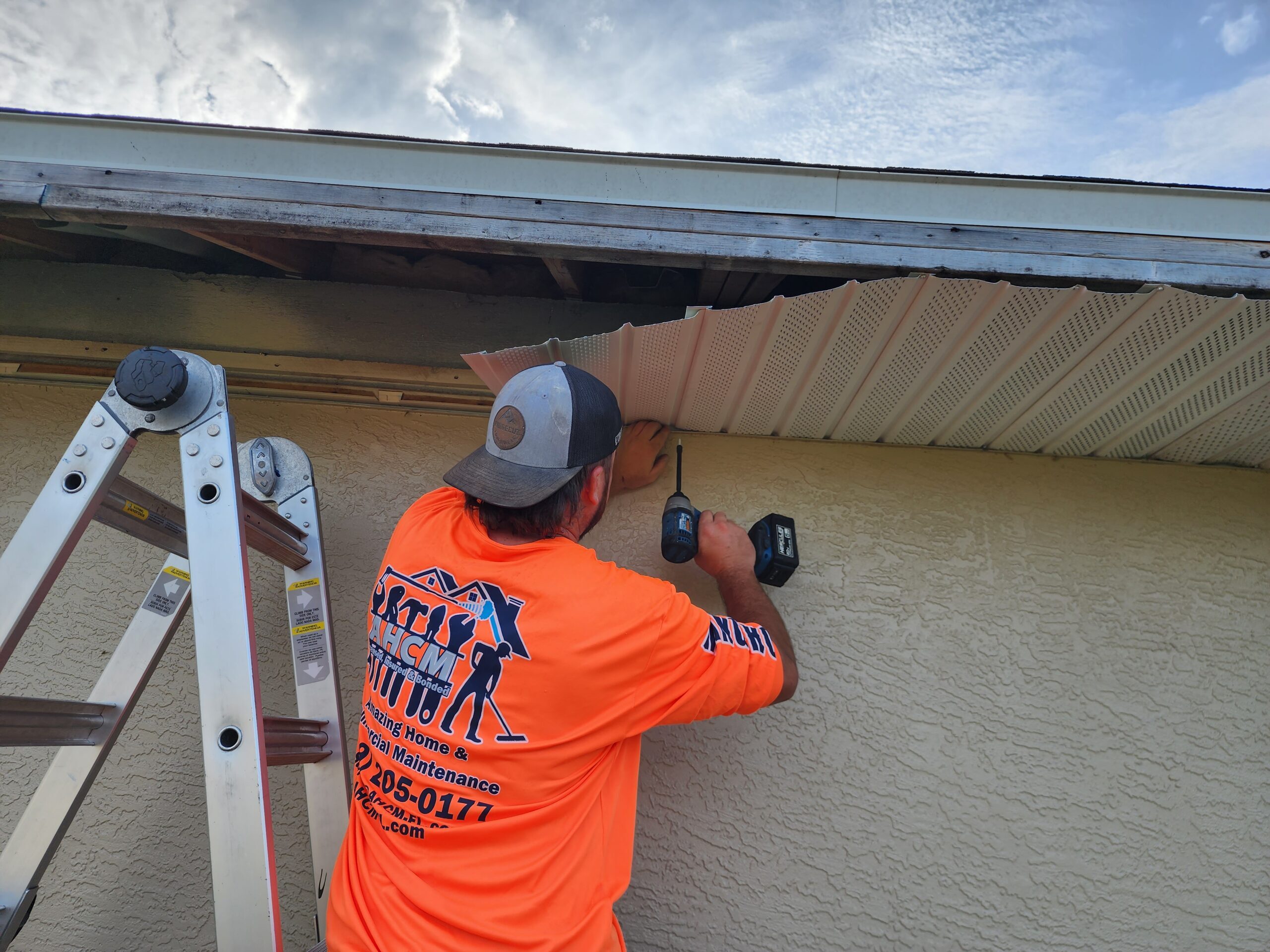 Worker installing soffit panel under house eaves