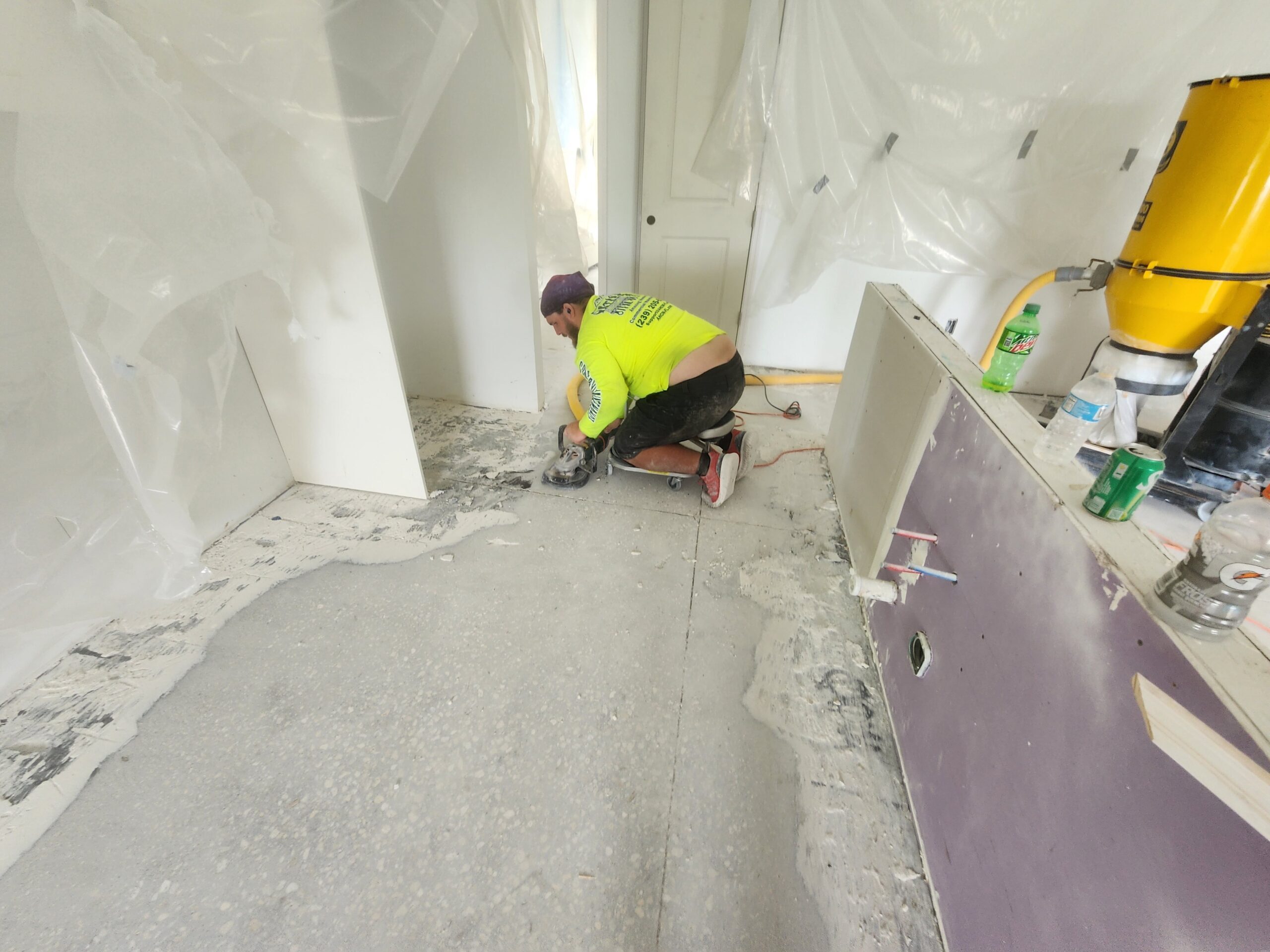 Worker grinding concrete floor in room renovation