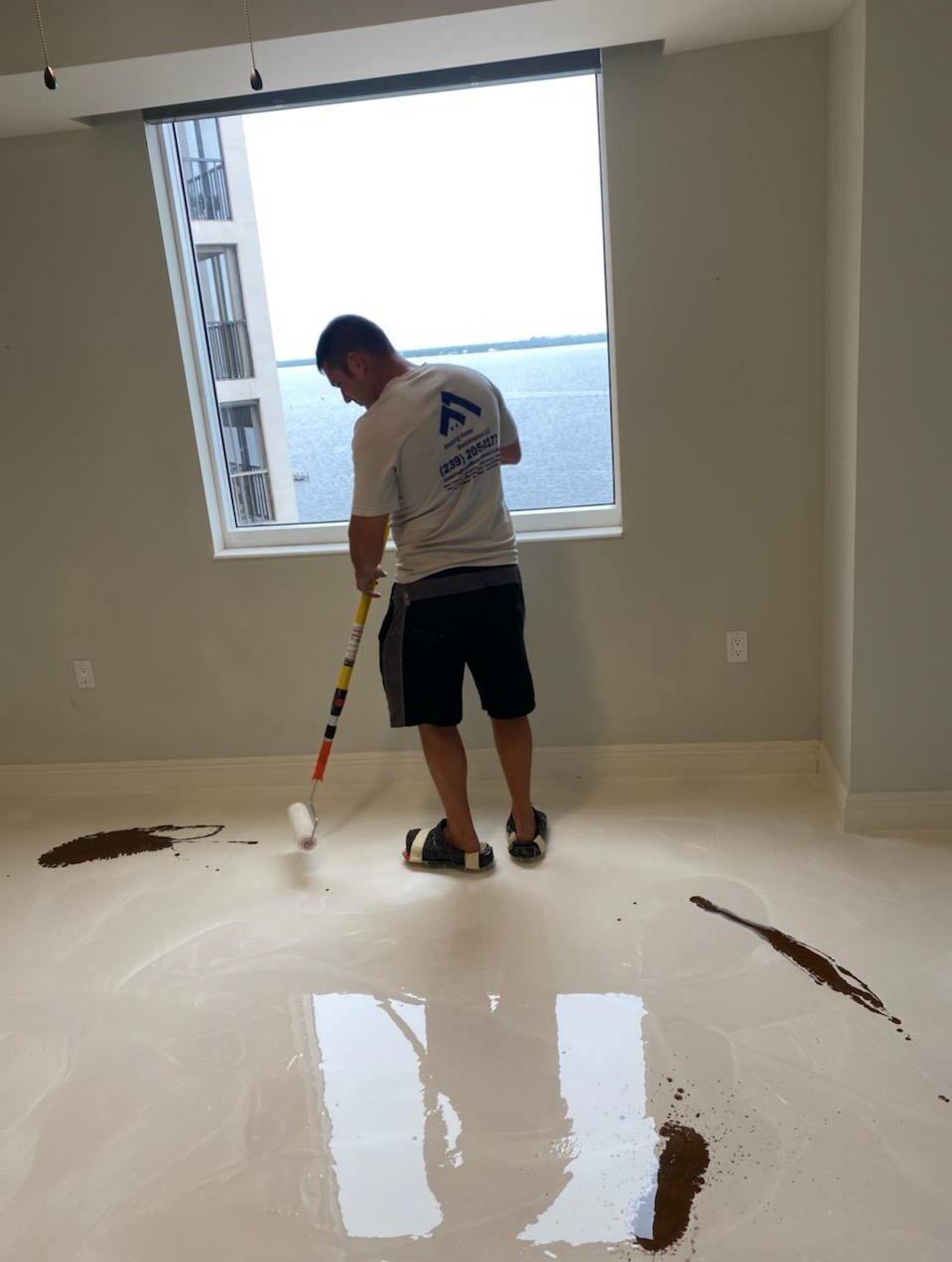 Worker rolling epoxy floor near window