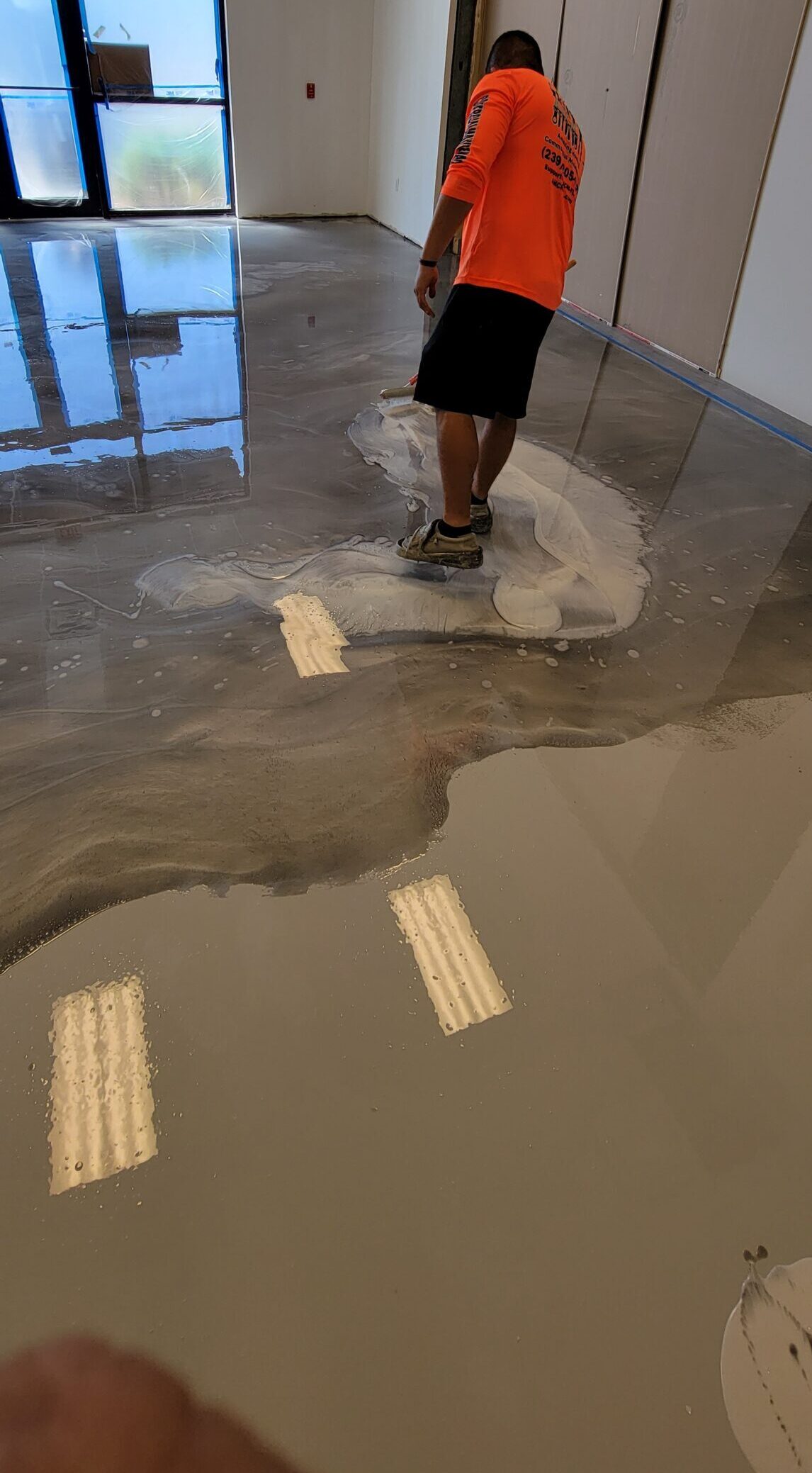 Worker applying liquid epoxy floor coating