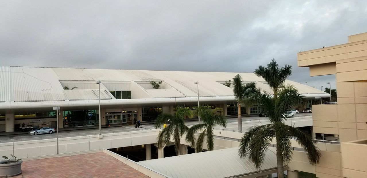 Airport terminal with palm trees and overcast sky