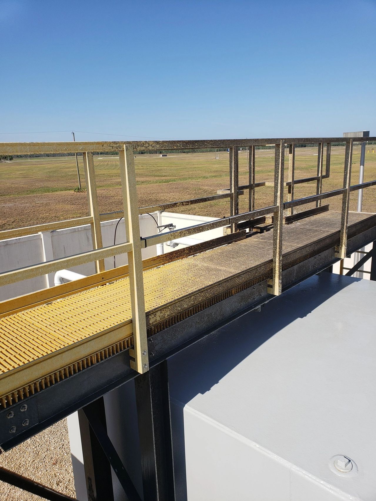 Elevated metal walkway overlooking grassy field