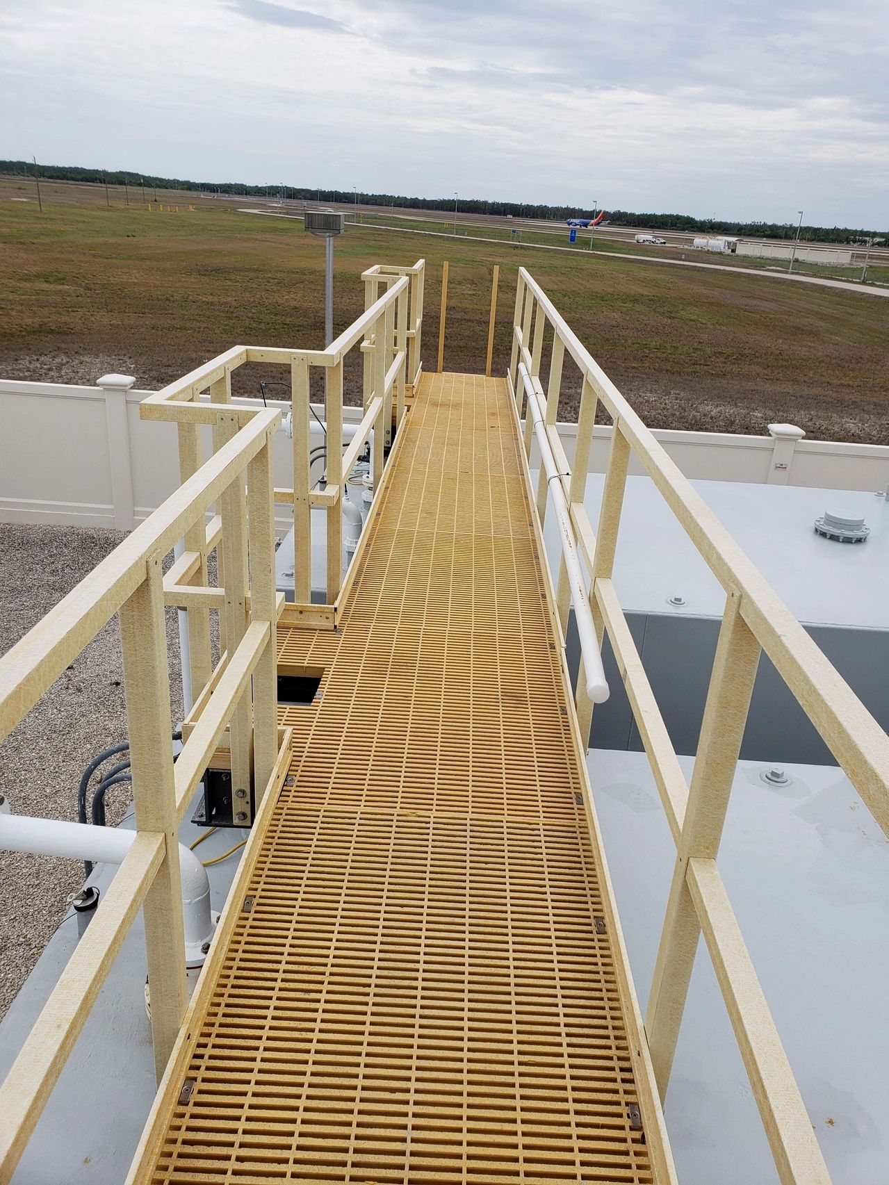 Yellow grated industrial catwalk over storage tanks