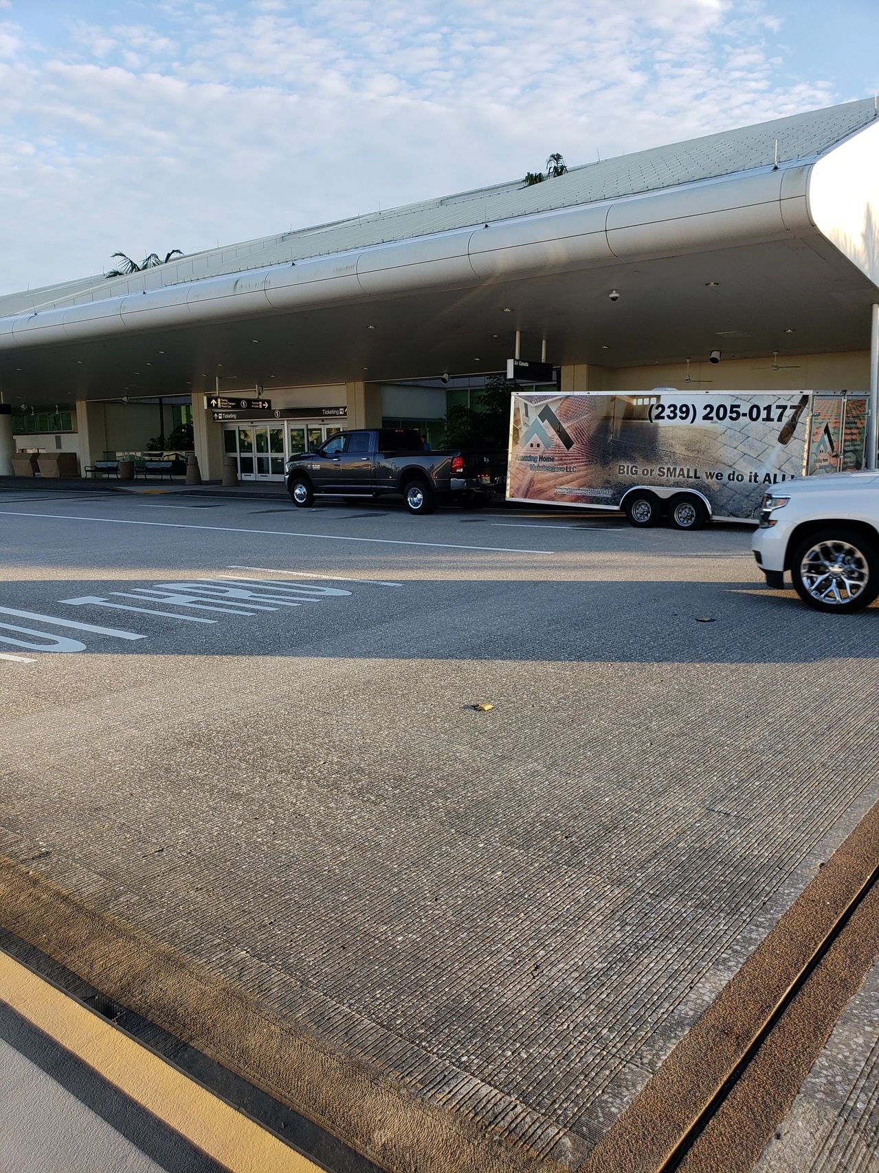 Airport curbside with parked truck and trailer