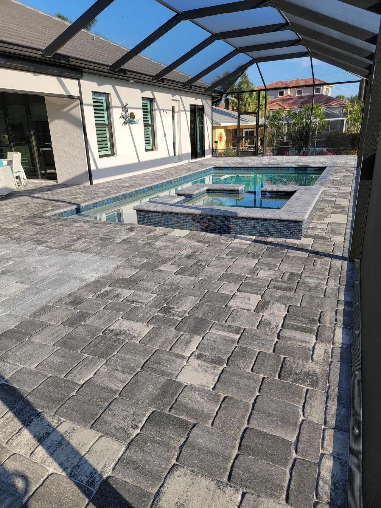 Screened backyard pool and spa with pavers