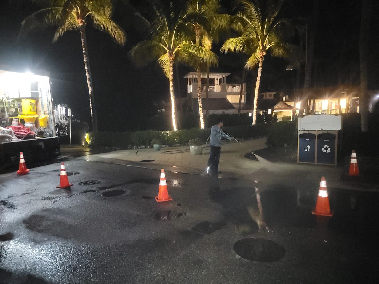 Worker repairing road at night with cones