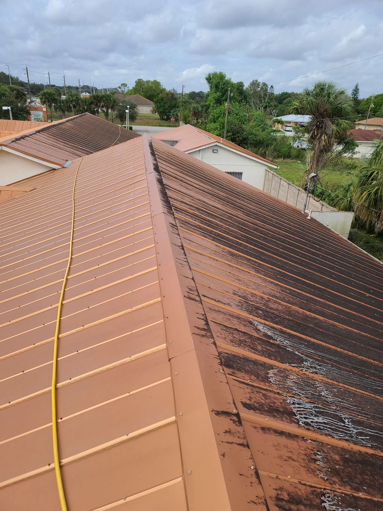 Rust-streaked metal roof with yellow hose