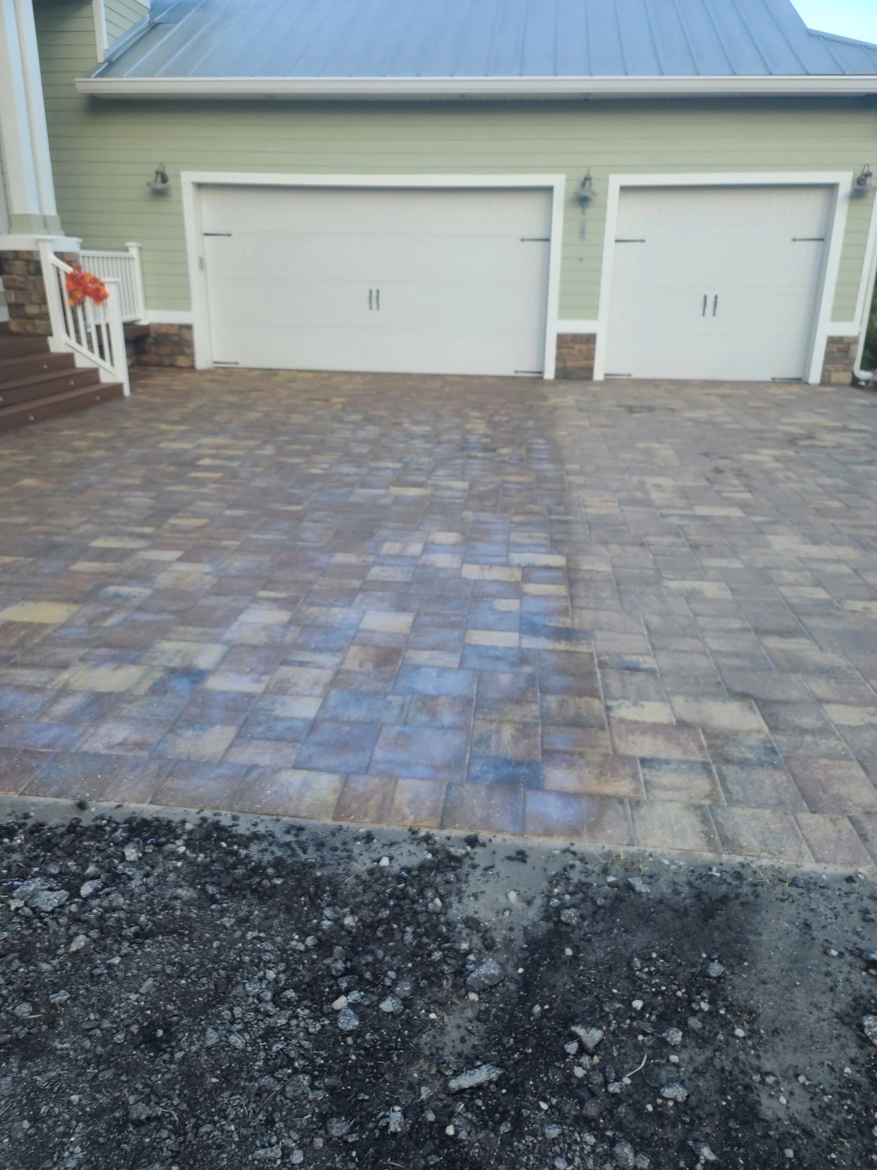 Paver driveway leading to two white garages